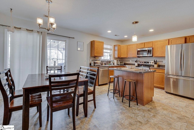 kitchen with a breakfast bar area, recessed lighting, stainless steel appliances, a kitchen island, and decorative light fixtures