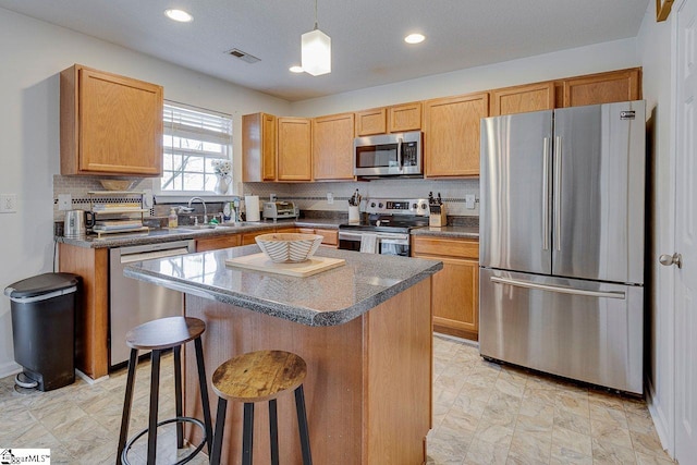 kitchen featuring stainless steel appliances, a sink, visible vents, a kitchen breakfast bar, and tasteful backsplash