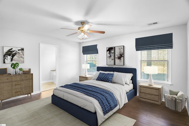 bedroom with connected bathroom, wood finished floors, visible vents, and a ceiling fan