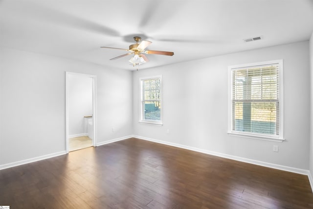 spare room featuring dark wood-style floors, baseboards, visible vents, and ceiling fan