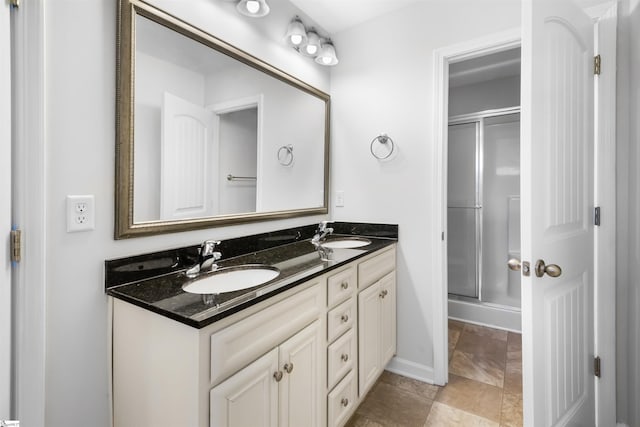 full bath featuring a stall shower, a sink, baseboards, and double vanity