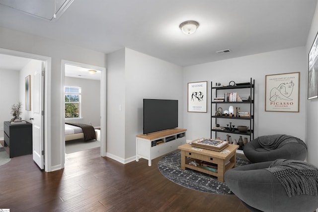 living area featuring attic access, dark wood-style flooring, visible vents, and baseboards