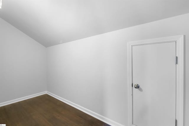 additional living space with dark wood-style floors, vaulted ceiling, and baseboards