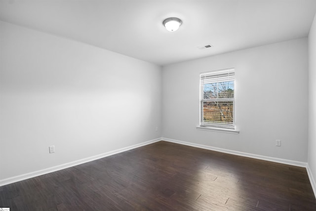 spare room featuring dark wood-style floors, visible vents, and baseboards