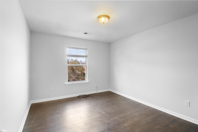 spare room with dark wood-style floors, visible vents, and baseboards