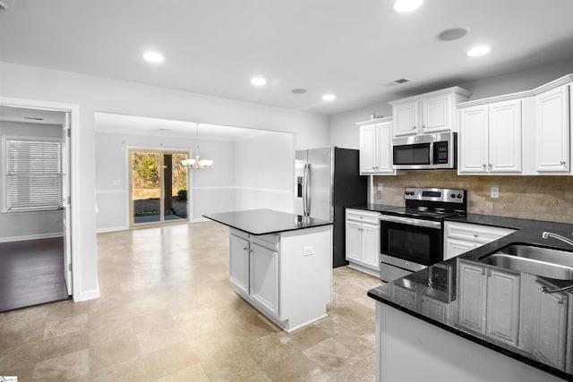 kitchen with appliances with stainless steel finishes, a sink, decorative backsplash, and a kitchen island