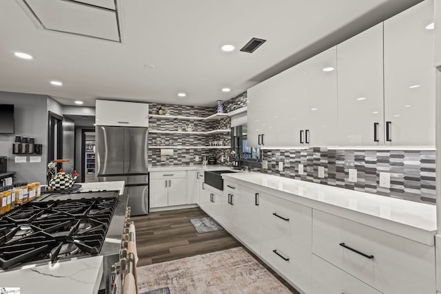 kitchen with appliances with stainless steel finishes, visible vents, white cabinetry, and tasteful backsplash