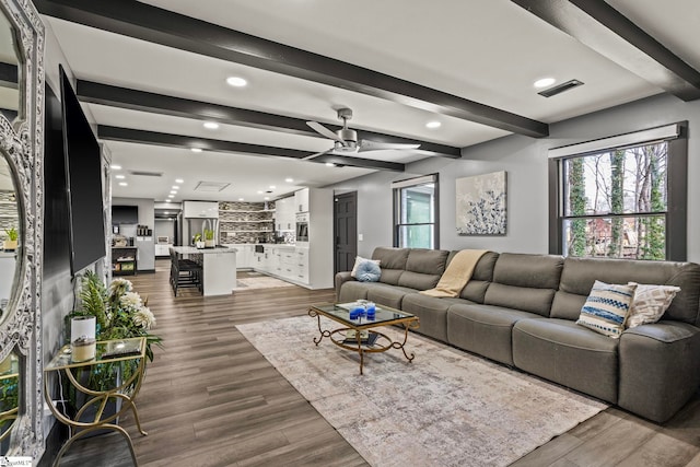 living area with visible vents, ceiling fan, beamed ceiling, wood finished floors, and recessed lighting