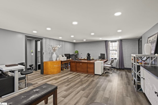 office with brick wall, wood finished floors, and recessed lighting