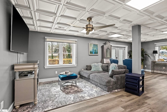 living area with wood finished floors, an ornate ceiling, and baseboards