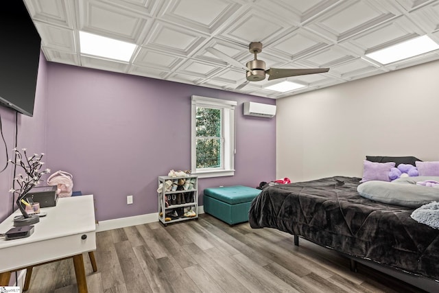 bedroom featuring an ornate ceiling, an AC wall unit, baseboards, and wood finished floors