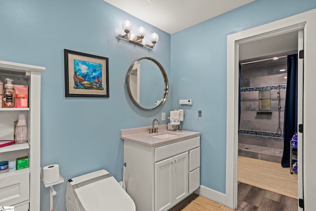 full bath featuring tiled shower, wood finished floors, vanity, and baseboards