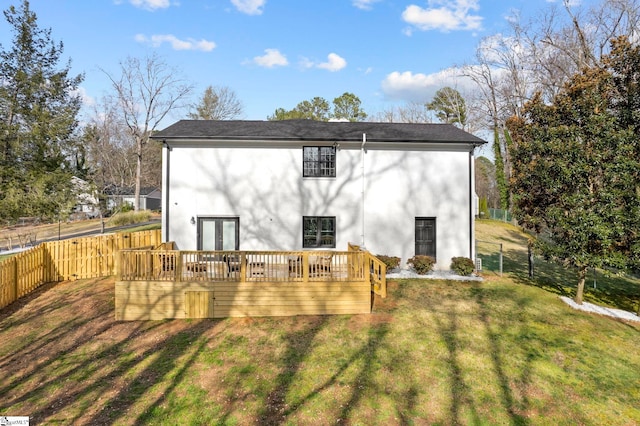 rear view of property featuring a fenced backyard, a yard, french doors, a wooden deck, and stucco siding