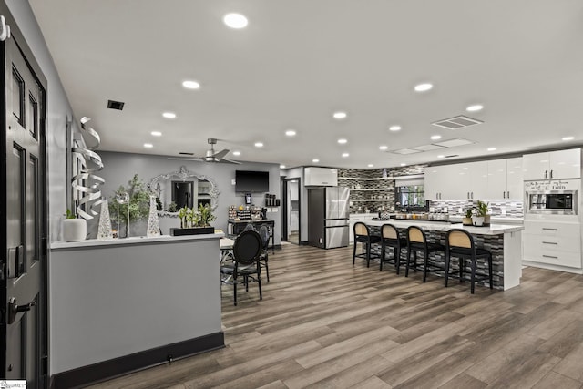 kitchen featuring white cabinets, modern cabinets, a kitchen island, a kitchen breakfast bar, and stainless steel appliances