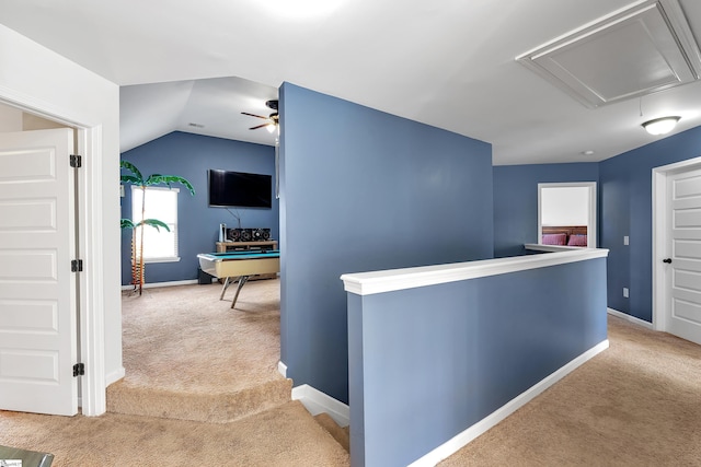 hall featuring carpet floors, an upstairs landing, baseboards, vaulted ceiling, and attic access