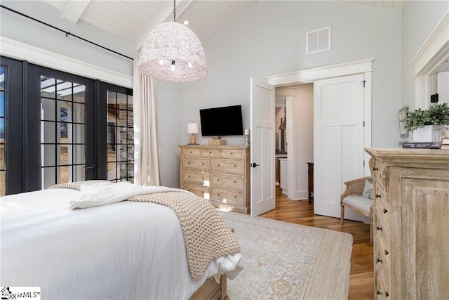 bedroom with visible vents, wood finished floors, high vaulted ceiling, wooden ceiling, and beamed ceiling