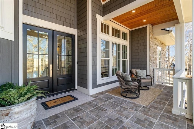 view of exterior entry featuring covered porch and french doors