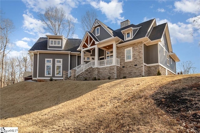 craftsman-style home featuring a porch, stone siding, and a chimney