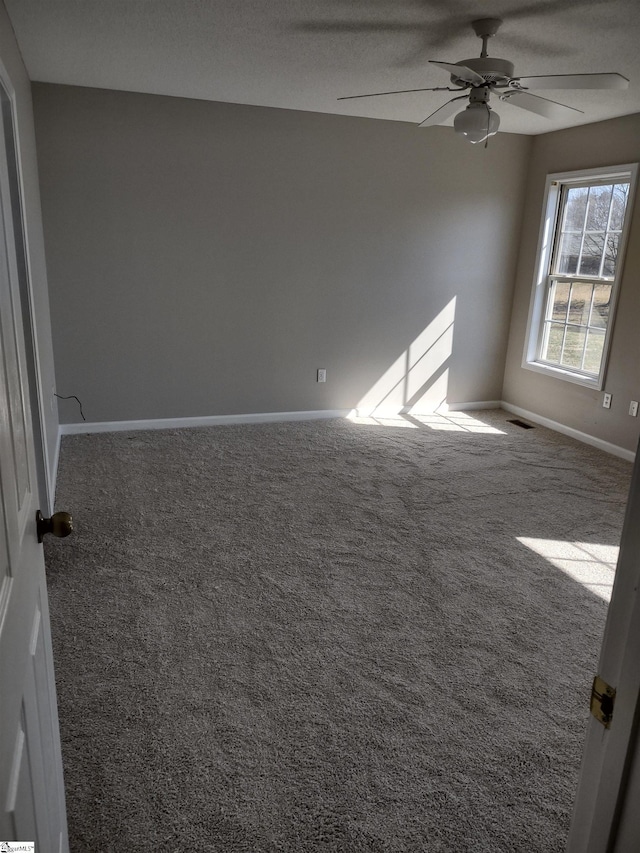 empty room with ceiling fan, carpet, visible vents, and baseboards