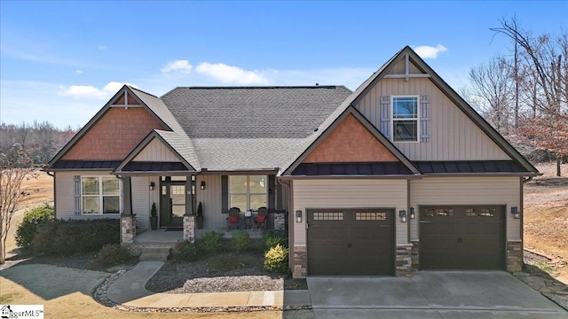 craftsman inspired home with covered porch, a standing seam roof, metal roof, stone siding, and driveway