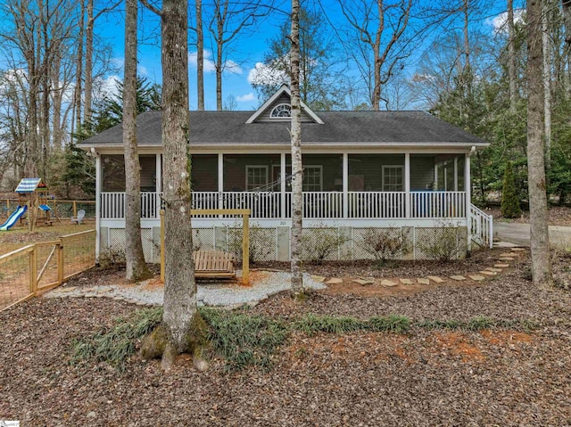 view of front facade with a porch, a playground, a shingled roof, fence, and a sunroom