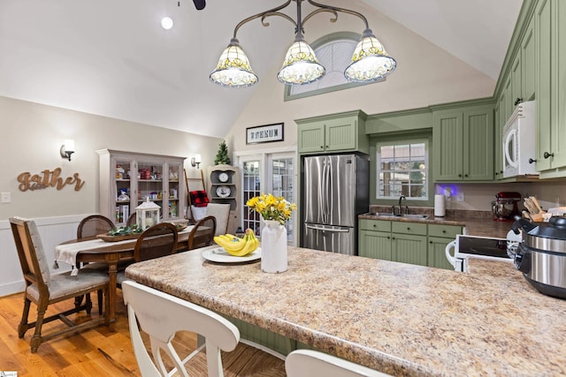 kitchen featuring light wood-style floors, white appliances, green cabinetry, and a kitchen bar