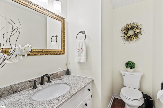 bathroom featuring baseboards, vanity, toilet, and wood finished floors