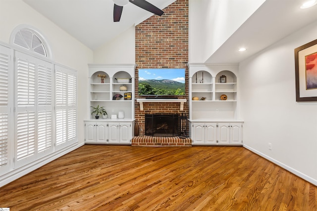 unfurnished living room with plenty of natural light, a fireplace, a ceiling fan, and wood finished floors