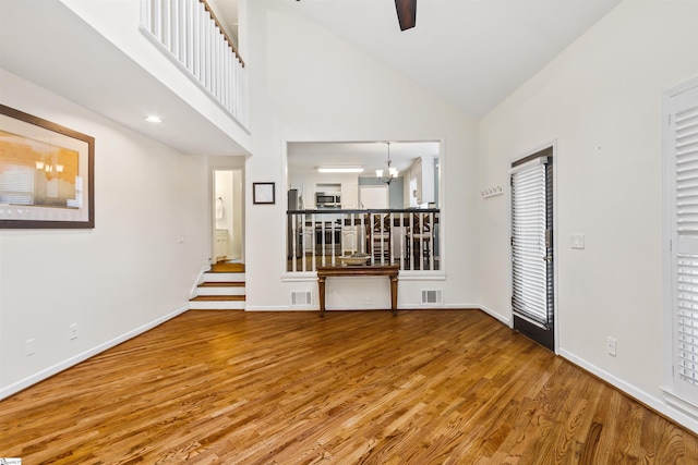 empty room featuring high vaulted ceiling, visible vents, baseboards, and wood finished floors