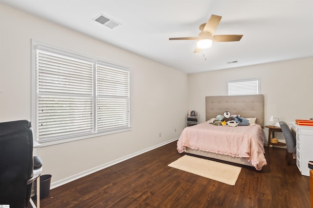 bedroom with a ceiling fan, visible vents, baseboards, and wood finished floors