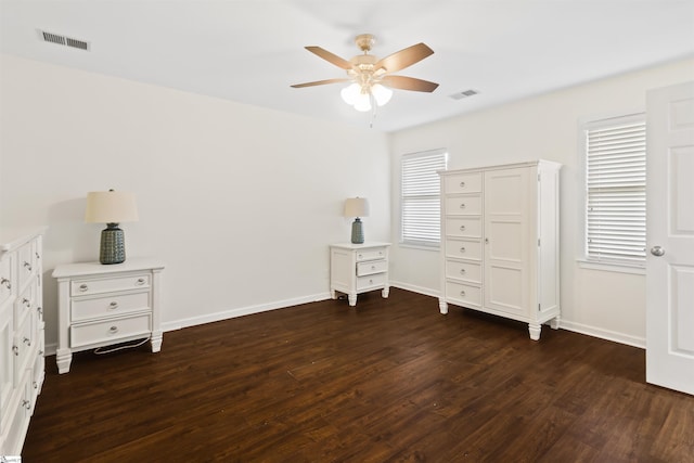 unfurnished bedroom with dark wood-style flooring, visible vents, and baseboards