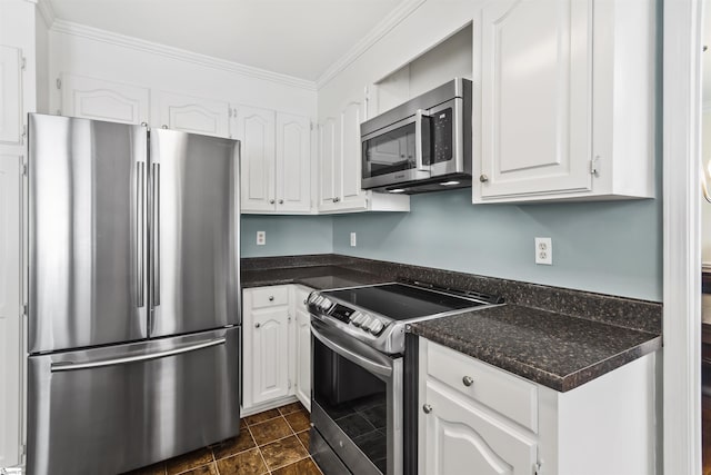 kitchen with appliances with stainless steel finishes, dark countertops, white cabinets, and ornamental molding