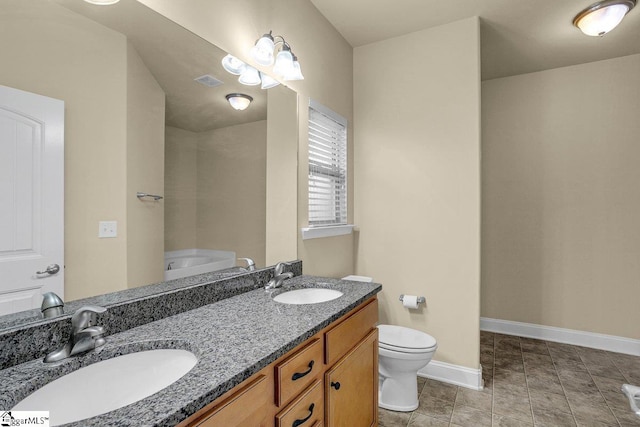 bathroom with toilet, double vanity, baseboards, and a sink