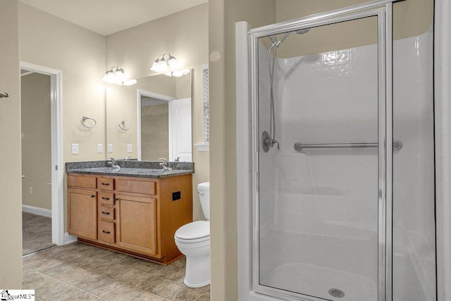 bathroom featuring a sink, a shower stall, toilet, and double vanity