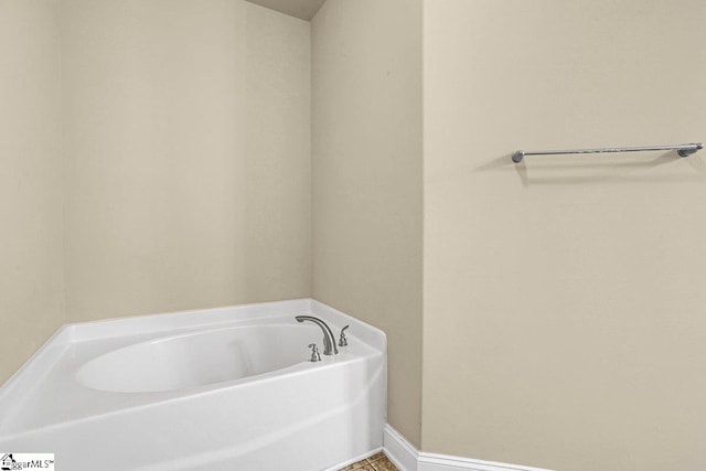 full bathroom with a garden tub and baseboards