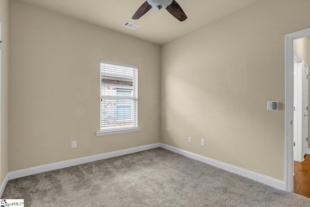 carpeted empty room with baseboards, visible vents, and a ceiling fan