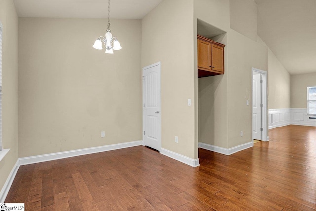 interior space with high vaulted ceiling, baseboards, an inviting chandelier, and wood finished floors