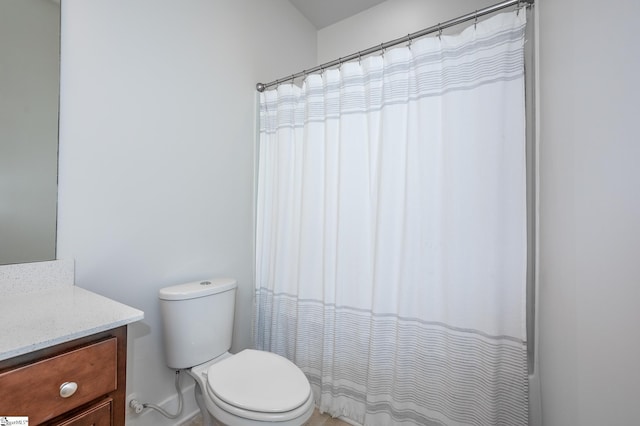 bathroom featuring toilet, curtained shower, and vanity