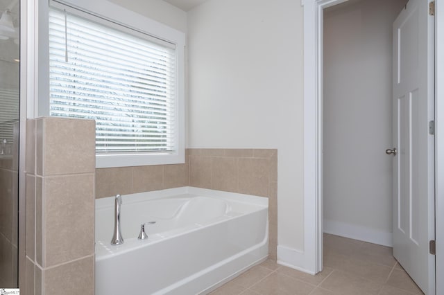 bathroom with baseboards, a shower with door, a bath, and tile patterned floors