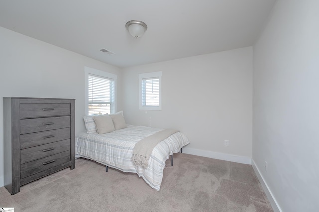 bedroom with light carpet, visible vents, and baseboards