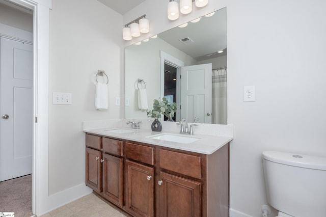 bathroom featuring toilet, double vanity, a sink, and visible vents