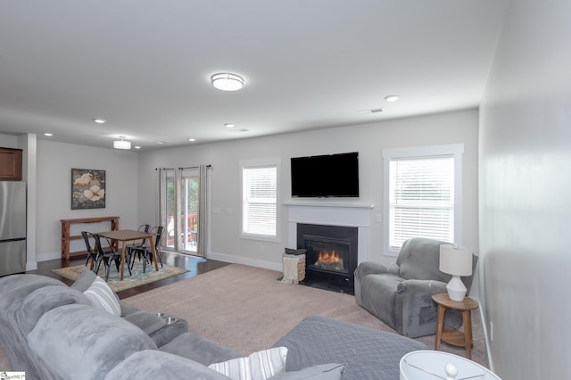 living area featuring recessed lighting, a fireplace with flush hearth, visible vents, and baseboards