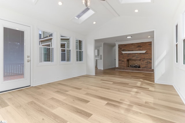 unfurnished living room with light wood-type flooring, lofted ceiling with skylight, baseboards, and visible vents