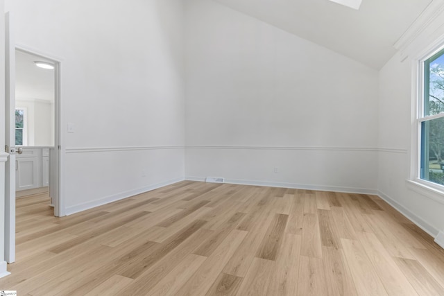 unfurnished room with light wood-style floors, vaulted ceiling, and baseboards