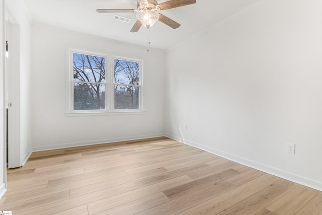 spare room with light wood-style floors, visible vents, crown molding, and baseboards