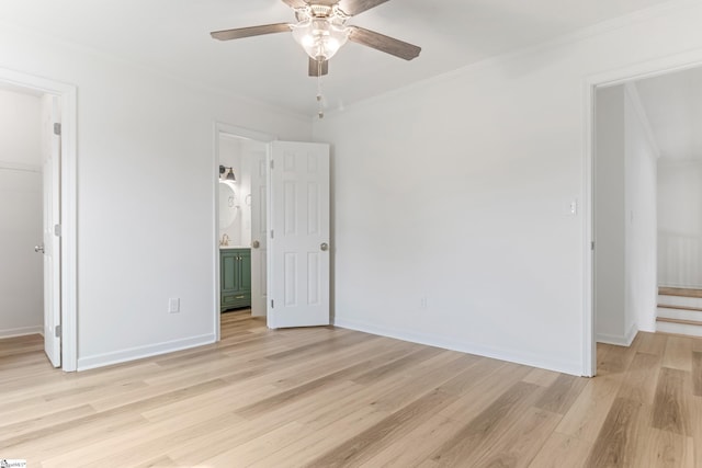 spare room with ceiling fan, ornamental molding, light wood-style flooring, and baseboards