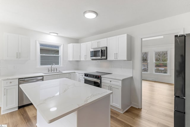 kitchen featuring appliances with stainless steel finishes, plenty of natural light, a sink, and a kitchen island