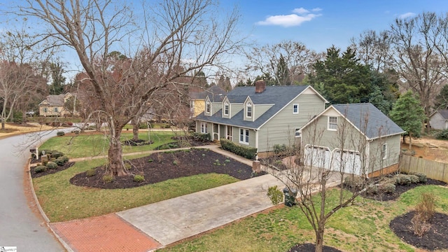 view of front of house with a chimney, a front yard, fence, a garage, and driveway