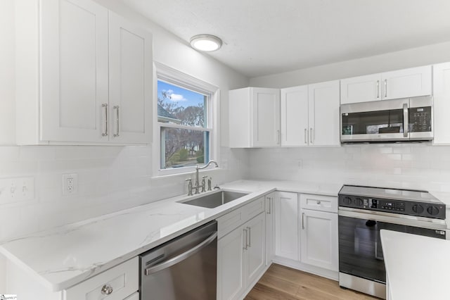 kitchen featuring appliances with stainless steel finishes, a sink, light wood-style flooring, and white cabinets