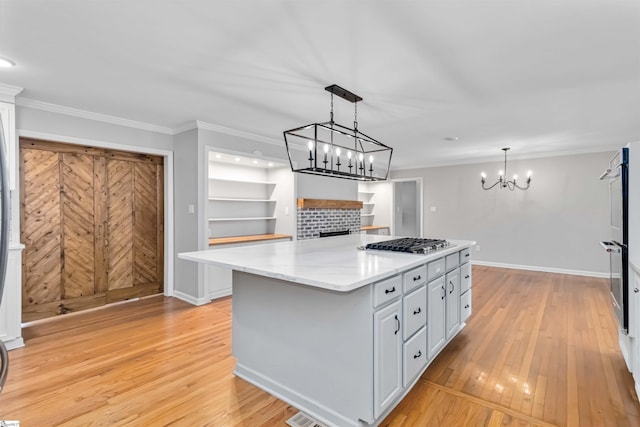 kitchen featuring crown molding, light wood-type flooring, stainless steel gas stovetop, and a kitchen island